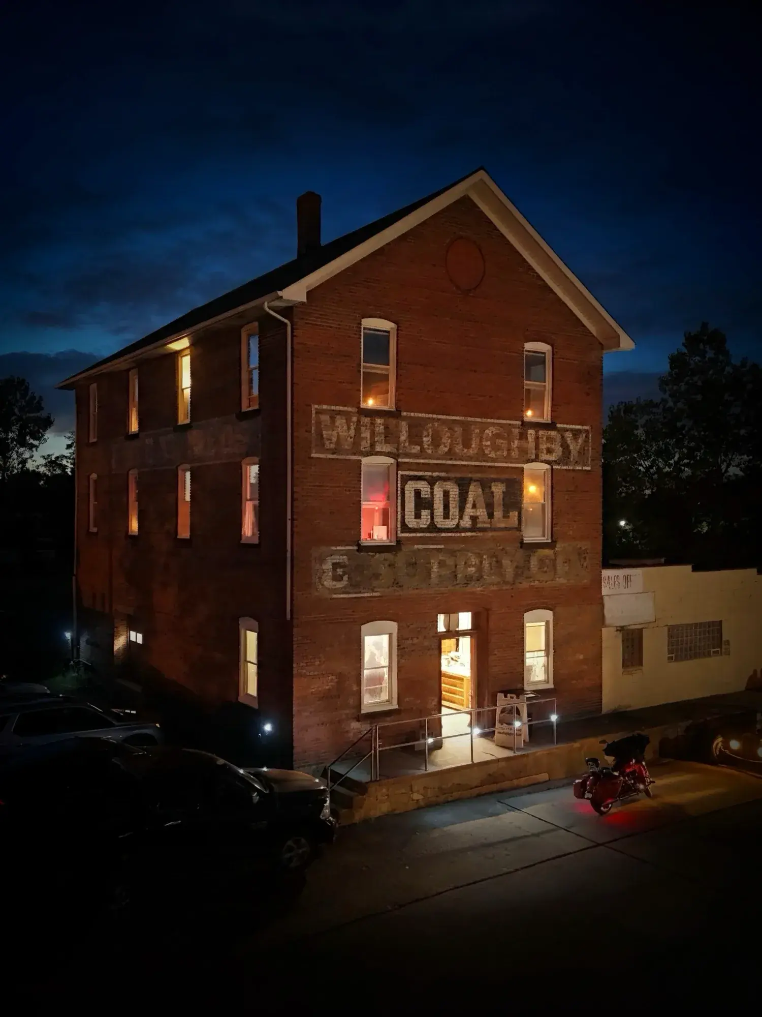 Willoughby Coal building at dusk with warmly lit windows and painted signage